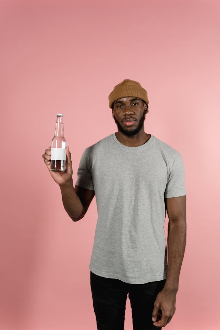 Portrait of a man with a bottle in front of a pink background. Ideal for mockups.